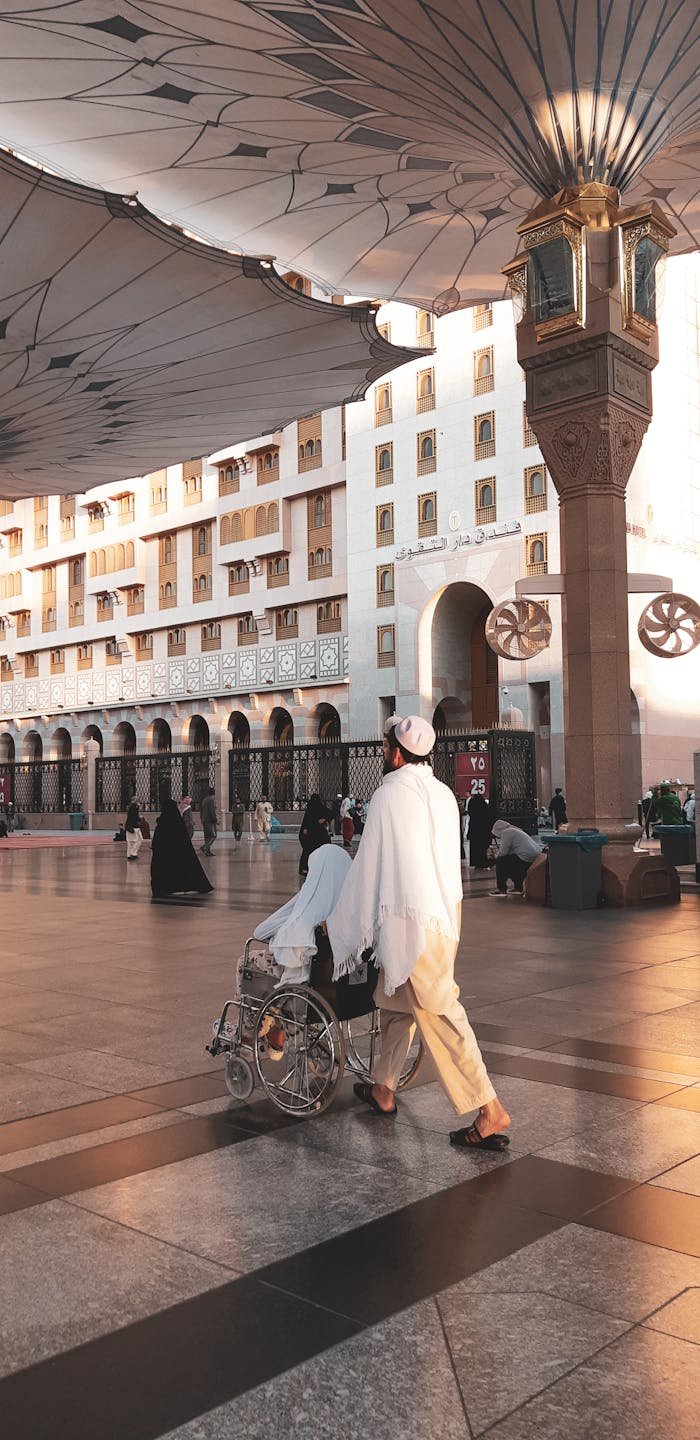 A man assisting a woman in a wheelchair at a mosque in Medina, Saudi Arabia.
